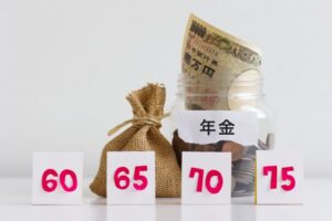 「年金」と書かれた紙幣と硬貨入りの瓶、麻袋と、60・65・70・75の数字カード